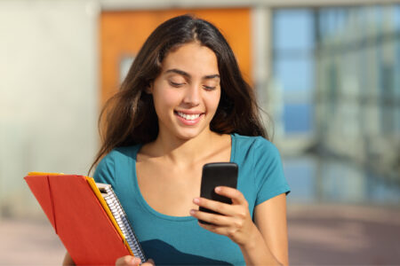 college age female in turquoise colored shirt, holding folder and phone